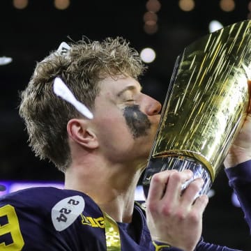 Michigan quarterback J.J. McCarthy kisses the championship trophy to celebrate the Wolverines' 34-13 win over Washington in the national championship game at NRG Stadium in Houston on Monday, Jan. 8, 2024.