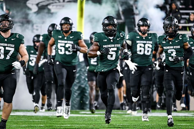 Michigan State's Nathan Carter, center, and the team take the field before the football game against Purdue.
