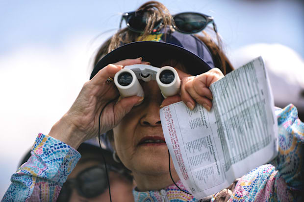 A patron watches the 2025 Masters through binoculars.