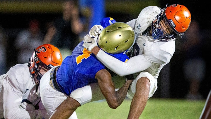 Benjamin linebacker Adam Balogoun-ali, right, and Patrick Downes, left, stop Cardinal Newman running back Jaylin Brown during their football game on October 20, 2023 in West Palm Beach, Florida. Benjamin linebacker Adam Balogoun-ali, right, and Patrick Downes, left, stop Cardinal Newman running back Jaylin Brown during their football game on October 20, 2023 in West Palm Beach, Florida.