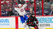 Mar 28, 2025; Raleigh, North Carolina, USA;  Montreal Canadiens right wing Josh Anderson (17) side steps a check by Carolina Hurricanes defenseman Jalen Chatfield (5) during the second period at Lenovo Center. Mandatory Credit: James Guillory-Imagn Images