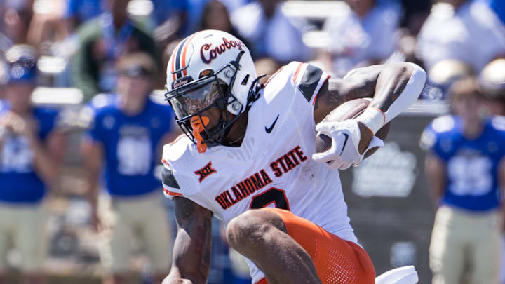 Sep 14, 2024; Tulsa, Oklahoma, USA;  Oklahoma State Cowboys running back Ollie Gordon II (0) keeps his balance as he runs the ball against Tulsa Golden Hurricane safety Zach Williams (18) and safety Buddha Garrett (24) during the third quarter at Skelly Field at H.A. Chapman Stadium. Mandatory Credit: Brett Rojo-Imagn Images