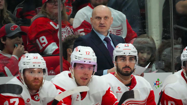 Mar 28, 2024; Raleigh, North Carolina, USA;  Detroit Red Wings head coach Derek Lalonde looks on from behind the bench against the Carolina Hurricanes during the second period at PNC Arena. Mandatory Credit: James Guillory-Imagn Images