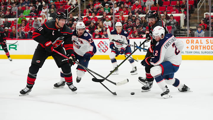 Dec 15, 2024; Raleigh, North Carolina, USA;  Carolina Hurricanes center Jordan Staal (11) with left wing William Carrier (28) gets the shot away against Columbus Blue Jackets defenseman Jake Christiansen (2) and center Sean Monahan (23) during the first period at Lenovo Center. Mandatory Credit: James Guillory-Imagn Images