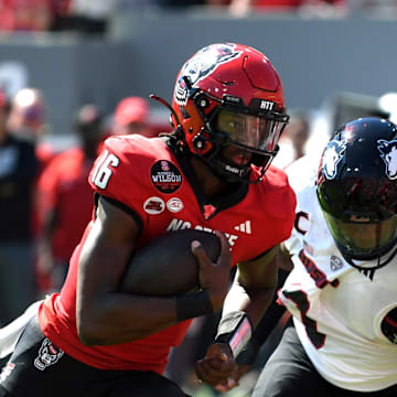 Sep 28, 2024; Raleigh, North Carolina, USA; North Carolina State Wolfpack quarter back CJ Bailey (16) runs the ball for a touchdown against the Northern Illinois Huskies in the first quarter at Carter-Finley Stadium. Mandatory Credit: Zachary Taft-Imagn Images
