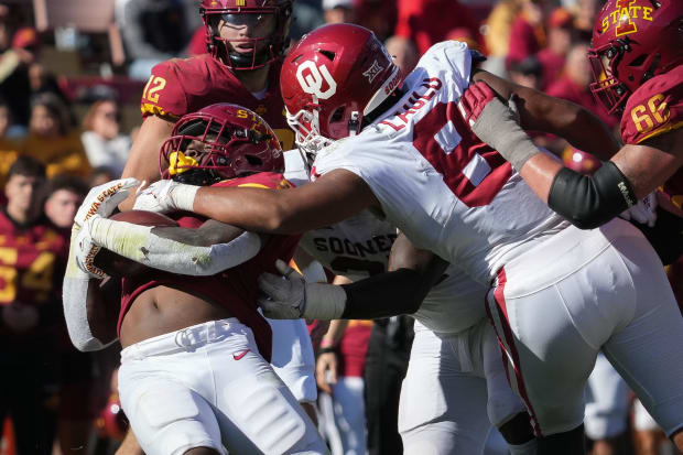 Football player Jonah Laulu makes a tackle in a white jersey.