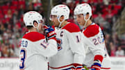 Mar 28, 2025; Raleigh, North Carolina, USA;  Montreal Canadiens right wing Cole Caufield (13) center Nick Suzuki (14) and left wing Juraj Slafkovský (20) talk against the Carolina Hurricanes during the second period at Lenovo Center. Mandatory Credit: James Guillory-Imagn Images