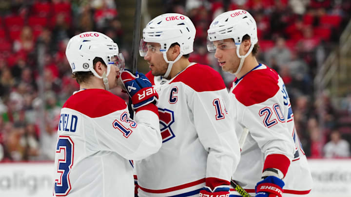Mar 28, 2025; Raleigh, North Carolina, USA;  Montreal Canadiens right wing Cole Caufield (13) center Nick Suzuki (14) and left wing Juraj Slafkovský (20) talk against the Carolina Hurricanes during the second period at Lenovo Center. Mandatory Credit: James Guillory-Imagn Images