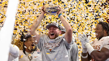 Jan 1, 2025; Atlanta, GA, USA; Texas Longhorns quarterback Quinn Ewers (3) holds up the trophy after a victory over the Arizona State Sun Devils in the Peach Bowl at Mercedes-Benz Stadium.