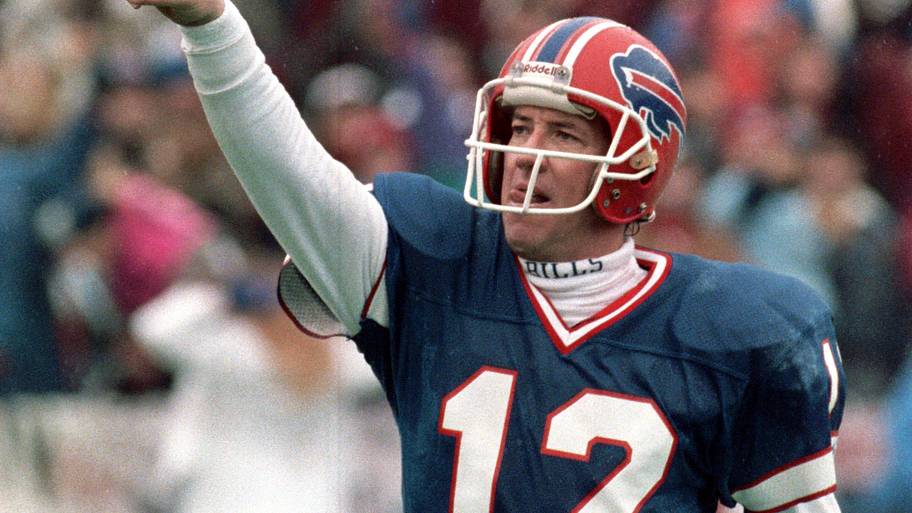 Buffalo Bills quarterback Jim Kelly pointing to the sky after throwing a touchdown pass during an NFL game