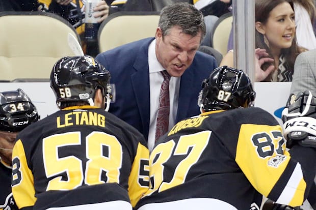 Hockey coach talks to players on the bench