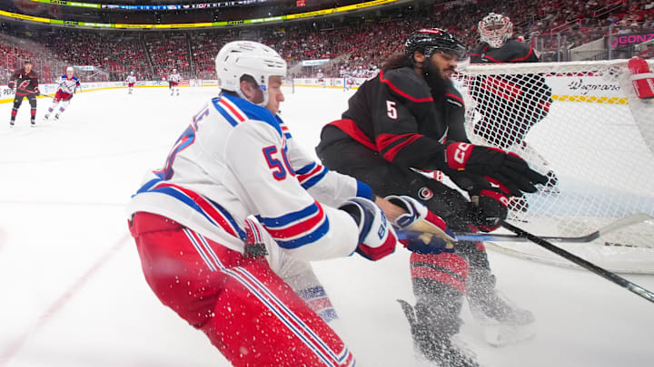 Apr 12, 2025; Raleigh, North Carolina, USA;  Carolina Hurricanes defenseman Jalen Chatfield (5) and New York Rangers left wing Will Cuylle (50) battle during the third period at Lenovo Center. Mandatory Credit: James Guillory-Imagn Images