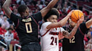 Louisville’s Chucky Hepburn splits Florida State defenders Taylor Bol Bowen, left, and Malique Ewin, right on his way to the basket during a game at the YUM Center. Feb. 22, 2025