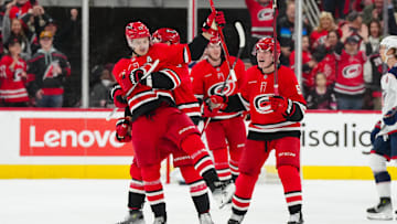 Jan 23, 2025; Raleigh, North Carolina, USA;  Carolina Hurricanes center Sebastian Aho (20) celebrates his goal with defenseman Dmitry Orlov (7) and  defenseman Jalen Chatfield (5) and right wing Jackson Blake (53) against the Columbus Blue Jackets during the second period at Lenovo Center. Mandatory Credit: James Guillory-Imagn Images