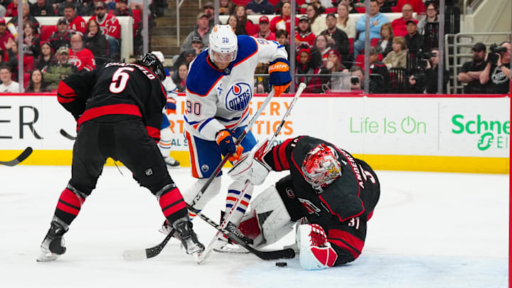 Mar 1, 2025; Raleigh, North Carolina, USA;  Carolina Hurricanes goaltender Frederik Andersen (31) and defenseman Jalen Chatfield (5) stop the scoring chance by Edmonton Oilers right wing Corey Perry (90) during the second period at Lenovo Center. Mandatory Credit: James Guillory-Imagn Images