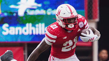 Oct 25, 2025; Lincoln, Nebraska, USA; Nebraska Cornhuskers running back Emmett Johnson (21) runs with the ball against Northwestern Wildcats defensive lineman Carmine Bastone (1) during the third quarter at Memorial Stadium. Mandatory Credit: Dylan Widger-Imagn Images