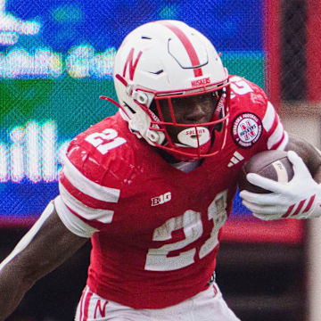 Oct 25, 2025; Lincoln, Nebraska, USA; Nebraska Cornhuskers running back Emmett Johnson (21) runs with the ball against Northwestern Wildcats defensive lineman Carmine Bastone (1) during the third quarter at Memorial Stadium. Mandatory Credit: Dylan Widger-Imagn Images