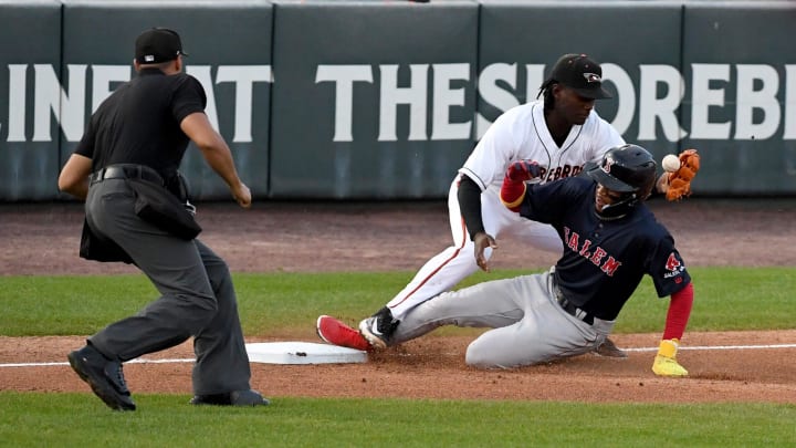 Shorebirds' Anderson De Los Santos (27) can't make the catch as Salem's Miguel Bleis (26) slides into third Tuesday, April 9, 2024, at Perdue Stadium in Salisbury, Maryland.