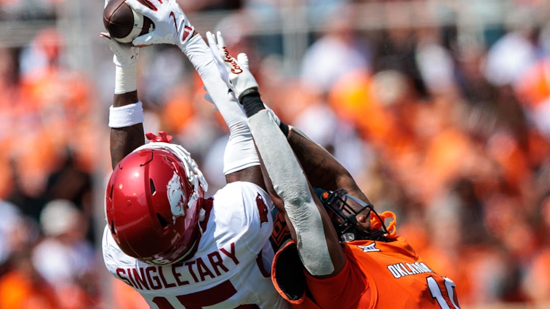 Sep 7, 2024; Stillwater, Oklahoma, USA; Arkansas Razorbacks defensive back Jaheim Singletary (15) makes an interception over Oklahoma State Cowboys wide receiver Rashod Owens (10) during the second quarter at Boone Pickens Stadium. Mandatory Credit: William Purnell-Imagn Images