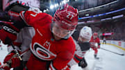 Dec 28, 2024; Raleigh, North Carolina, USA; Carolina Hurricanes center Tyson Jost (27) is checked by New Jersey Devils center Curtis Lazar (42) during the first period at Lenovo Center. Mandatory Credit: James Guillory-Imagn Images