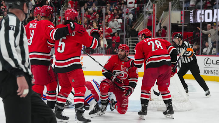Dec 29, 2025; Raleigh, North Carolina, USA;  Carolina Hurricanes left wing Jordan Martinook (48) is congratulated by left wing William Carrier (28), defenseman Jalen Chatfield (5) and defenseman K'Andre Miller (19) after his goal against the New York Rangers during the third period at Lenovo Center. Mandatory Credit: James Guillory-Imagn Images