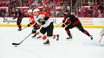 Nov 5, 2024; Raleigh, North Carolina, USA;  Philadelphia Flyers defenseman Jamie Drysdale (9) skates out of the defensive zone with the puck past Carolina Hurricanes left wing Eric Robinson (50) during the first period at Lenovo Center. Mandatory Credit: James Guillory-Imagn Images