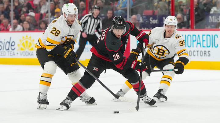 Apr 7, 2026; Raleigh, North Carolina, USA; Carolina Hurricanes defenseman Sean Walker (26) skates with the puck between Boston Bruins center Elias Lindholm (28) and center Morgan Geekie (39) during the third period at Lenovo Center. Mandatory Credit: James Guillory-Imagn Images Apr 7, 2026; Raleigh, North Carolina, USA; Carolina Hurricanes defenseman Sean Walker (26) skates with the puck between Boston Bruins center Elias Lindholm (28) and center Morgan Geekie (39) during the third period at Lenovo Center. Mandatory Credit: James Guillory-Imagn Images
