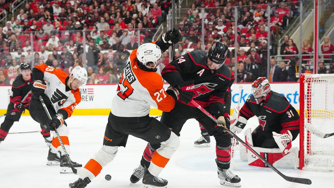 May 4, 2026; Raleigh, North Carolina, USA; Carolina Hurricanes defenseman Jaccob Slavin (74) and Philadelphia Flyers left wing Noah Cates (27) battle over the puck in the first overtime in game two of the second round of the 2026 Stanley Cup Playoffs at Lenovo Center. 