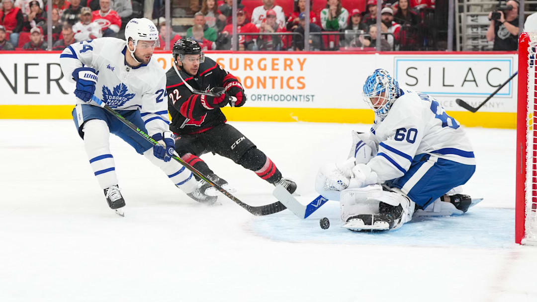 Dec 4, 2025; Raleigh, North Carolina, USA; Toronto Maple Leafs goaltender Joseph Woll (60) with center Scott Laughton (24) stops the scoring attempt by Carolina Hurricanes center Logan Stankoven (22) during the first period at Lenovo Center. Mandatory Credit: James Guillory-Imagn Images