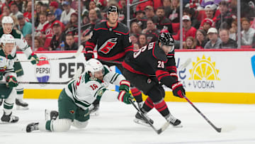 Nov 6, 2025; Raleigh, North Carolina, USA;  Minnesota Wild center Vinnie Hinostroza (18) and Carolina Hurricanes defenseman Sean Walker (26) battle over the puck during the second period at Lenovo Center. Mandatory Credit: James Guillory-Imagn Images