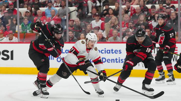 Apr 18, 2026; Raleigh, North Carolina, USA; Ottawa Senators center Ridly Greig (71) tries to skate with the puck past Carolina Hurricanes left wing Jordan Martinook (48) and defenseman K'andre Miller (19) during the second period in game one of the first round of the 2026 Stanley Cup Playoffs at Lenovo Center. Mandatory Credit: James Guillory-Imagn Images