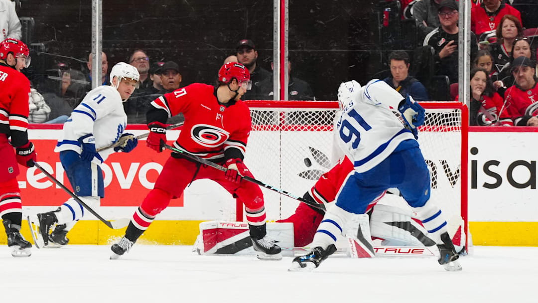 Apr 13, 2025; Raleigh, North Carolina, USA;  Toronto Maple Leafs center John Tavares (91) scores a goal past Carolina Hurricanes goaltender Frederik Andersen (31) and center Mark Jankowski (77) during the third period at Lenovo Center. Mandatory Credit: James Guillory-Imagn Images