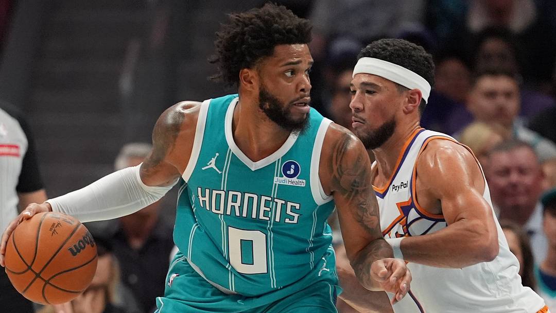 Apr 2, 2026; Charlotte, North Carolina, USA; Charlotte Hornets forward Miles Bridges (0) works the ball against Phoenix Suns guard Devin Booker (1)during the first quarter at Spectrum Center. Mandatory Credit: Jim Dedmon-Imagn Images