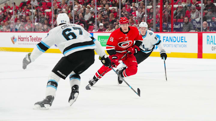 Feb 8, 2025; Raleigh, North Carolina, USA;  Carolina Hurricanes defenseman Scott Morrow (56) skates with the puck in between right wing Josh Doan (91) and y67 during the first period at Lenovo Center. Mandatory Credit: James Guillory-Imagn Images