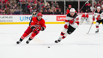 Dec 28, 2024; Raleigh, North Carolina, USA;  Carolina Hurricanes center Seth Jarvis (24) and New Jersey Devils center Jack Hughes (86) skate after the puck during the first period at Lenovo Center. Mandatory Credit: James Guillory-Imagn Images