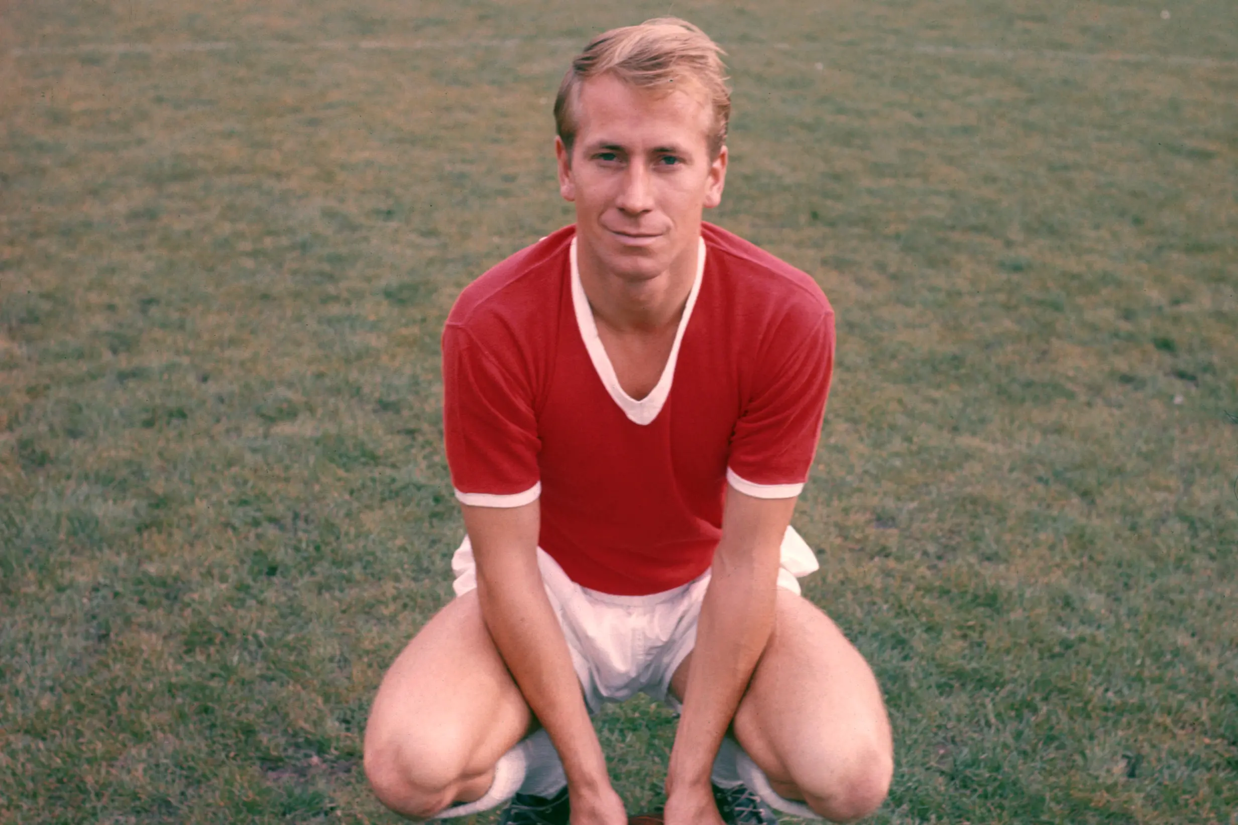 Bobby Charlton leaning on the ball.