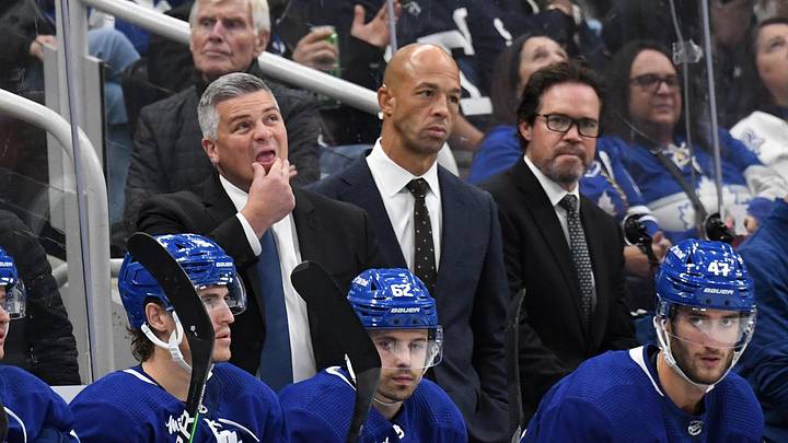 Oct 8, 2022; Toronto, Ontario, CAN;  Toronto Maple Leafs head coach Sheldon Keefe (left) looks up at the scoreboard as assistant coaches Manny Malhotra (center) and Dean Chynoweth look on during a break in play against the Detroit Red Wings at Scotiabank Arena. Mandatory Credit: Dan Hamilton-Imagn Images