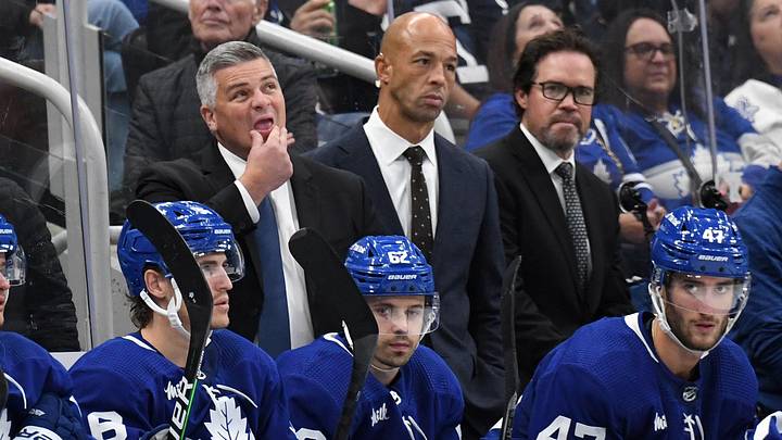 Oct 8, 2022; Toronto, Ontario, CAN;  Toronto Maple Leafs head coach Sheldon Keefe (left) looks up at the scoreboard as assistant coaches Manny Malhotra (center) and Dean Chynoweth look on during a break in play against the Detroit Red Wings at Scotiabank Arena. Mandatory Credit: Dan Hamilton-Imagn Images