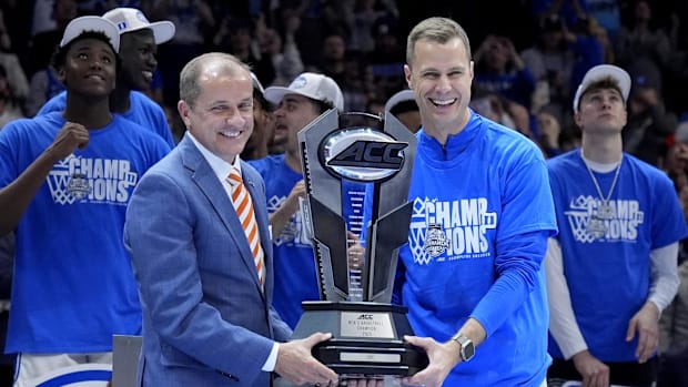  ACC Commissioner Jim Phillips hands the championship trophy to Duke Blue Devils head coach Jon Scheyer.