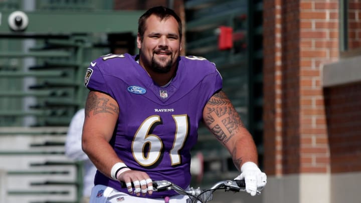 Baltimore Ravens center Nick Samac (61) rides a young fan's bicycle to a joint practice with the Green Bay Packers on Aug. 22, 2024 in Green Bay, Wis.