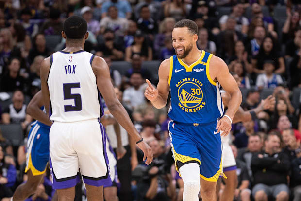 Golden State Warriors guard Stephen Curry (30) motions to Sacramento Kings guard De'Aaron Fox (5)