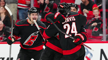 Nov 25, 2024; Raleigh, North Carolina, USA;  Carolina Hurricanes center Sebastian Aho (20) is congratulated by defenseman Dmitry Orlov (7) and center Seth Jarvis (24) after his goal against the Dallas Stars during the third period at Lenovo Center. Mandatory Credit: James Guillory-Imagn Images