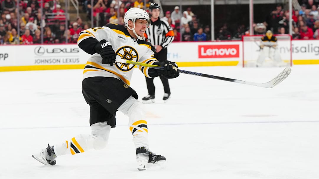 Oct 31, 2024; Raleigh, North Carolina, USA;  Boston Bruins defenseman Hampus Lindholm (27) takes a shot against the Carolina Hurricanes during the second period at Lenovo Center. Mandatory Credit: James Guillory-Imagn Images