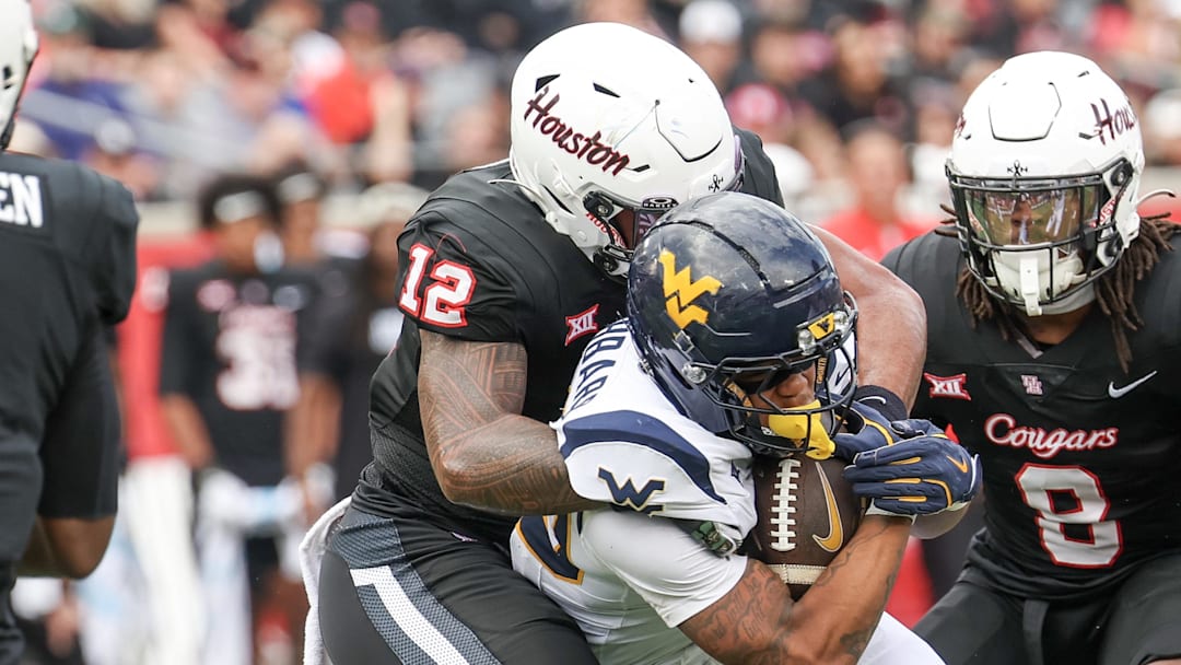 Nov 1, 2025; Houston, Texas, USA; West Virginia Mountaineers running back Diore Hubbard (20) is tackled by Houston Cougars linebacker Sione Fotu (12) in the first half at TDECU Stadium. Mandatory Credit: Thomas Shea-Imagn Images