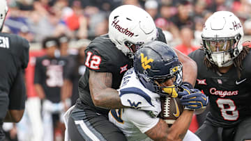 Nov 1, 2025; Houston, Texas, USA; West Virginia Mountaineers running back Diore Hubbard (20) is tackled by Houston Cougars linebacker Sione Fotu (12) in the first half at TDECU Stadium. Mandatory Credit: Thomas Shea-Imagn Images