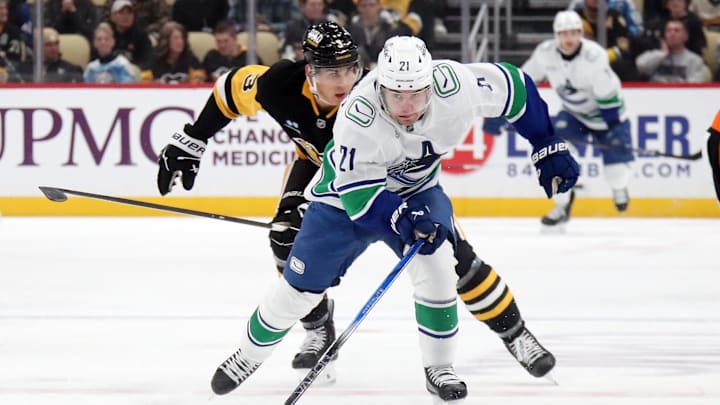 Nov 27, 2024; Pittsburgh, Pennsylvania, USA;  Vancouver Canucks left wing Nils Hoglander (21) chases the puck ahead of Pittsburgh Penguins defenseman Jack St. Ivany (3) during the second period at PPG Paints Arena. Mandatory Credit: Charles LeClaire-Imagn Images