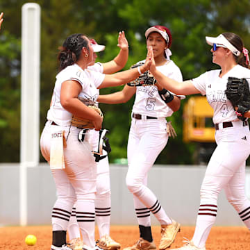 Mississippi State softball players high-five each other at the end of an inning during the 2024 season.