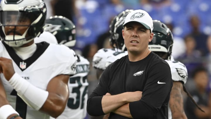 Aug 9, 2024; Baltimore, Maryland, USA;  Philadelphia Eagles offensive coordinator Kellen Moore looks on as quarterback Jalen Hurts (1) throws before a preseason game against the Baltimore Ravens at M&T Bank Stadium.