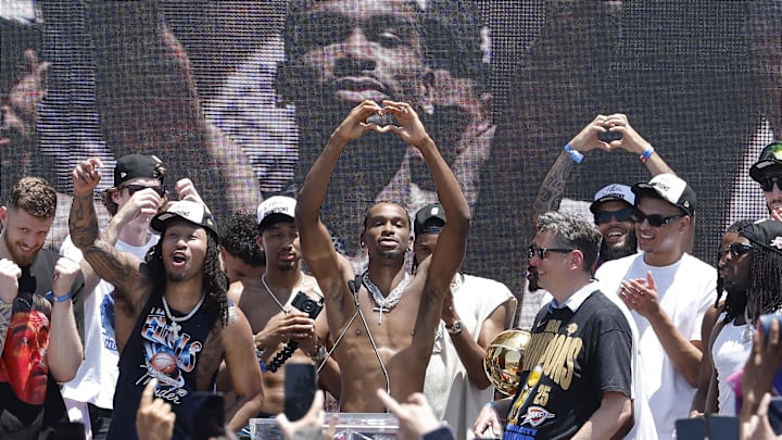 Jun 24, 2025; Oklahoma City, OK, USA; Oklahoma City Thunder guard Shai Gilgeous-Alexander, center, holds up a heart shape with his hands for fans during the Oklahoma City Thunder Champions parade. Center. Mandatory Credit: Alonzo Adams-Imagn Images