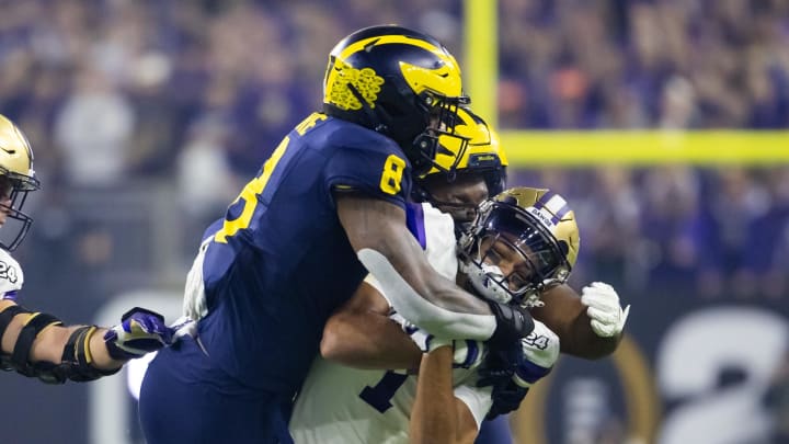 Jan 8, 2024; Houston, TX, USA; Michigan Wolverines linebacker Derrick Moore (8) and defensive back Will Johnson (2) tackle Washington Huskies wide receiver Derrick Moore (1) during the 2024 College Football Playoff national championship game at NRG Stadium. Mandatory Credit: Mark J. Rebilas-USA TODAY Sports